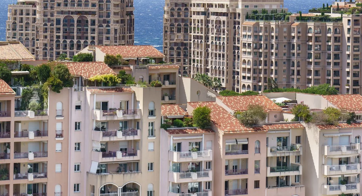 Panoramic view of luxury Mediterranean-style apartments in Monaco, with a backdrop of the blue sea.