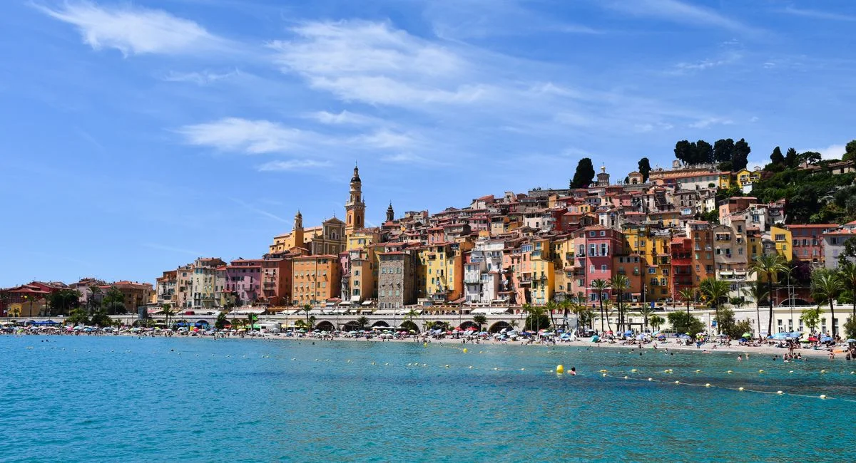 A vibrant view of Menton's coastline, showcasing colorful buildings and azure waters on a sunny day.