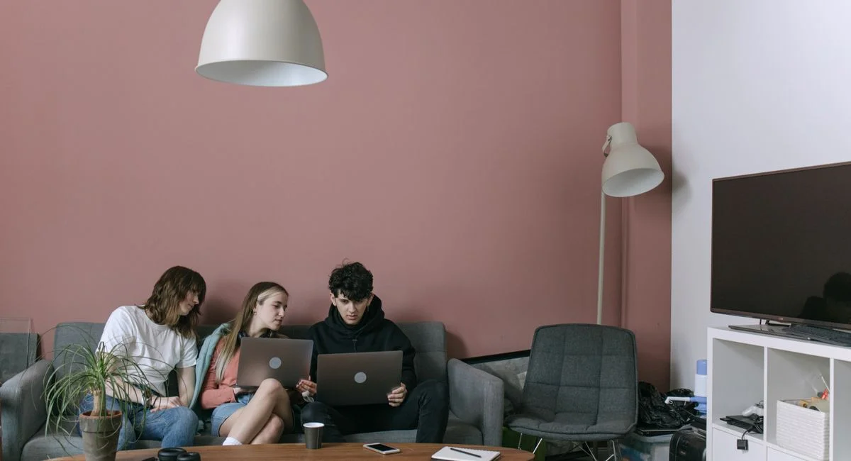 Adults discussing and working on laptops in a cozy living room setting.