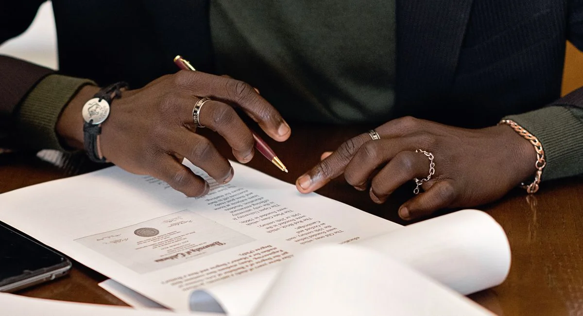 A business professional's hands signing a document at a desk, focusing on details.