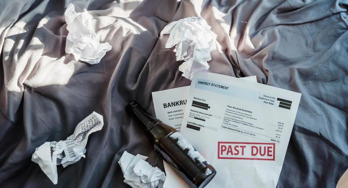 Scene of financial distress with bankruptcy notice, past due bills, and crumpled papers on a bed.