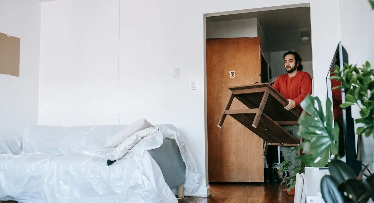 Man holding a wooden table during relocation in a contemporary apartment.