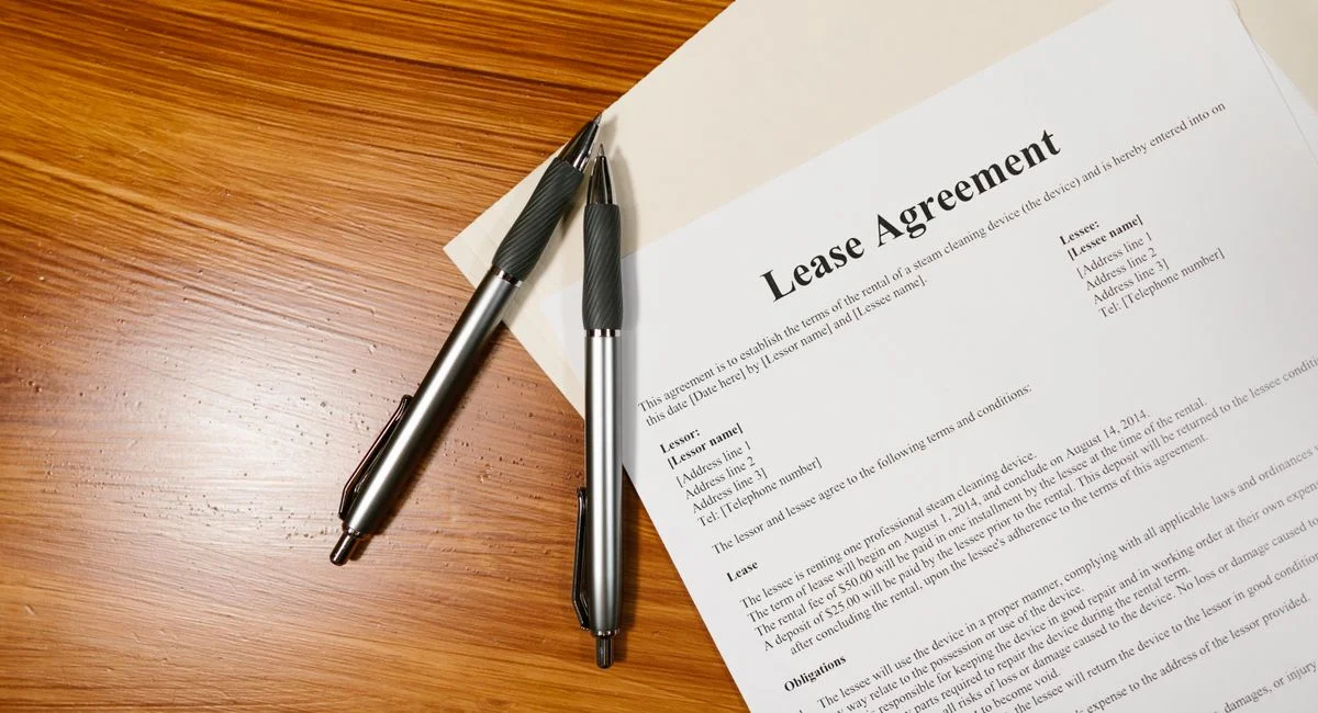 High-angle view of a lease agreement and pens on a wooden desk.