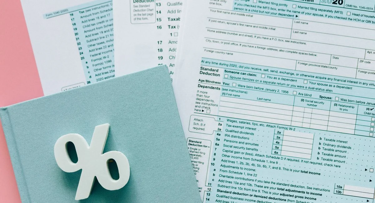 Tax documents with a percentage symbol on a pink and blue desk setup, emphasizing finance.