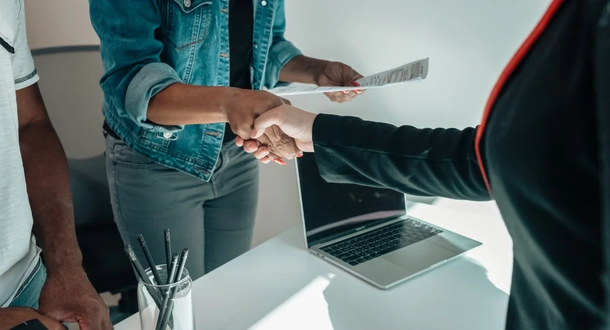 Two people shaking hands over a desk signifies a business agreement or partnership.