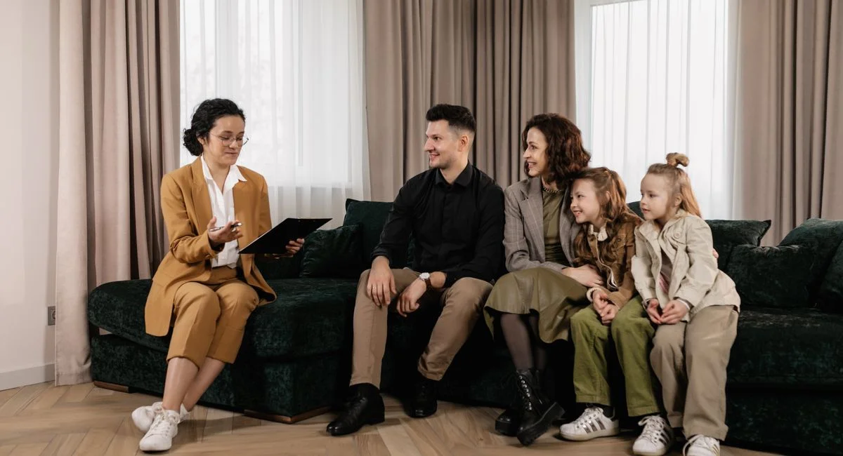 Family discussing home purchase options with real estate agent indoors.