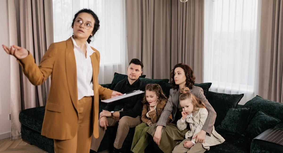 A real estate agent presenting property options to a family in a living room setting.