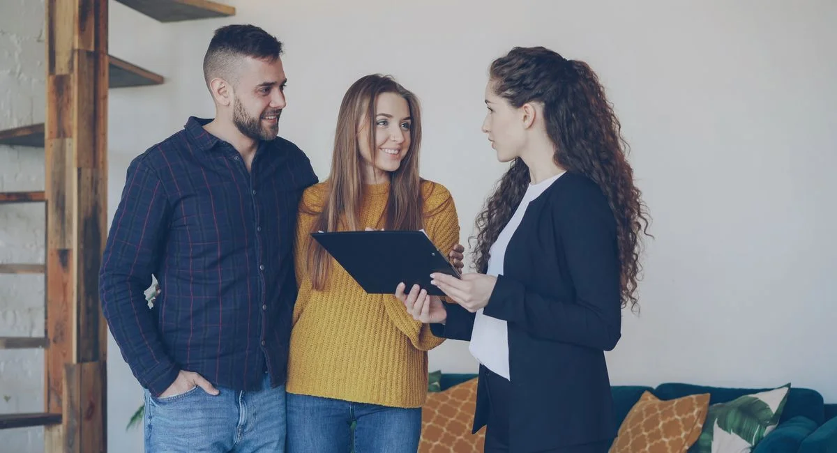 Couple discussing property options with a real estate agent indoors.
