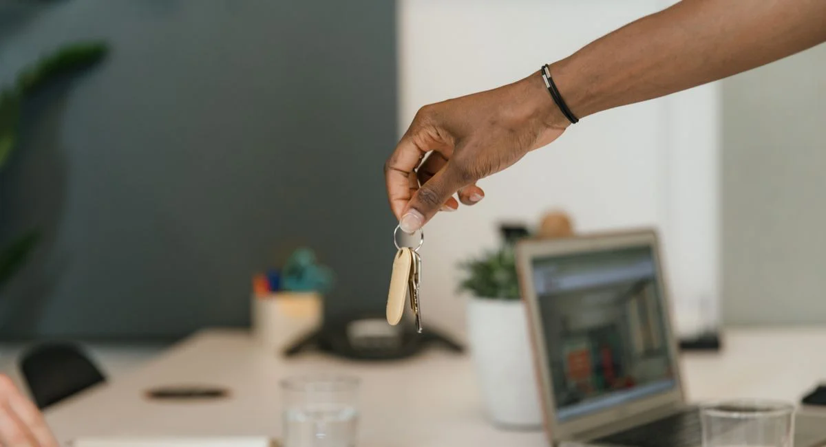 Close-up of a handshake exchanging keys in an office setting.