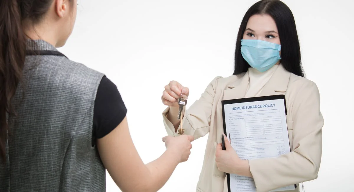 Real estate agent in a face mask hands keys to a client, illustrating safe business practices.