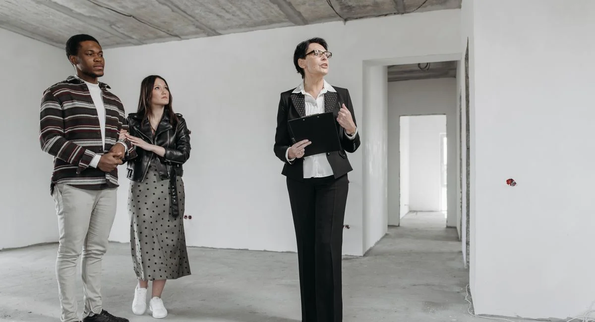 A real estate agent shows an unfinished apartment to prospective buyers.