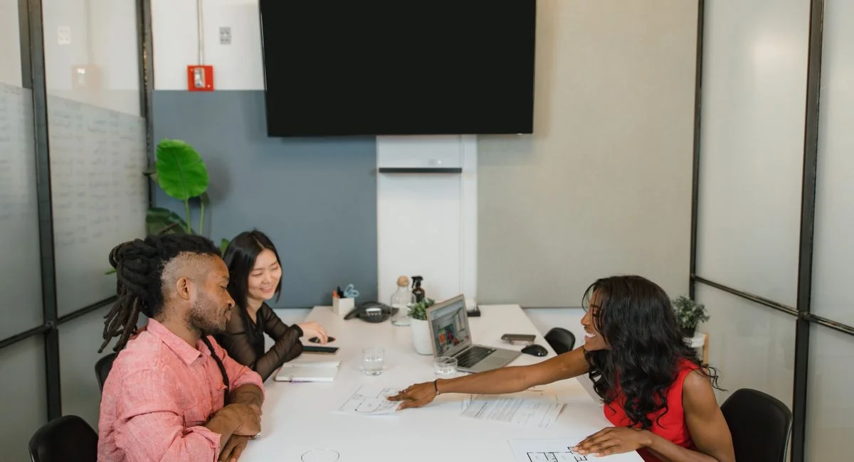 Three professionals engaged in a collaborative meeting in a modern office setting.