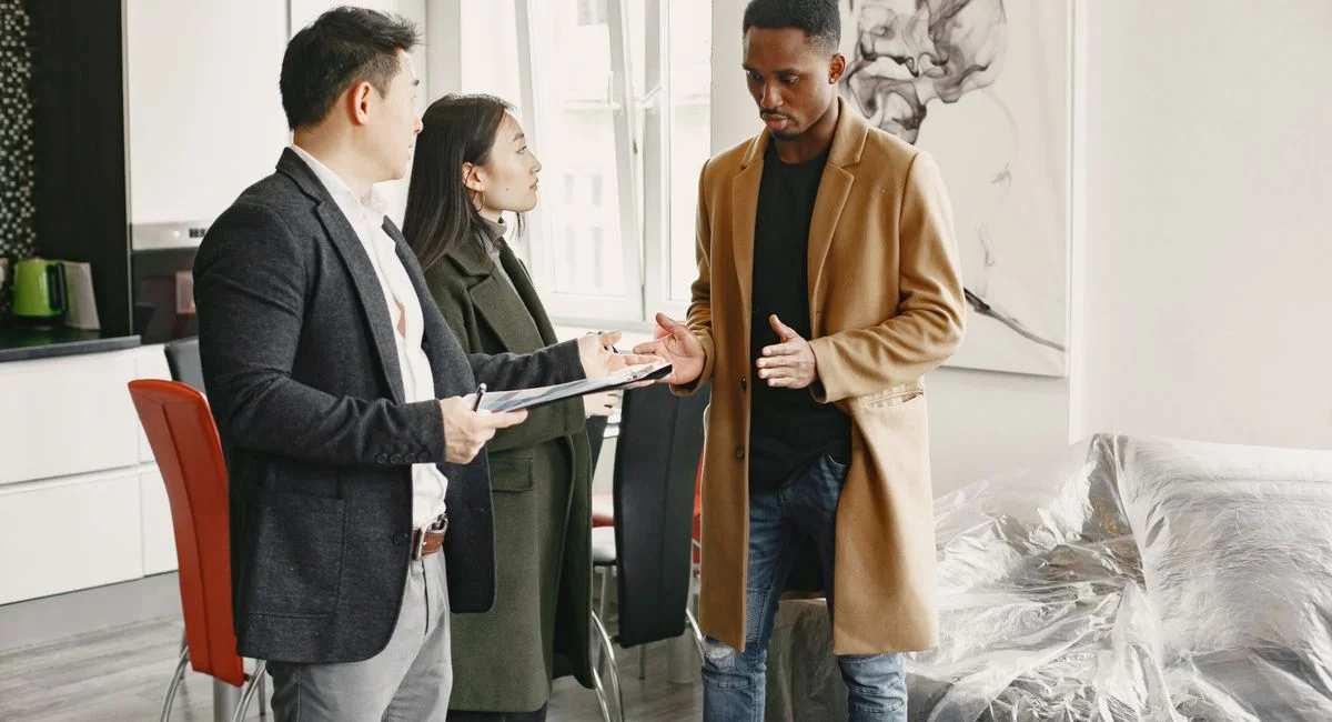 Three professionals engage in a conversation inside a contemporary office, promoting teamwork.