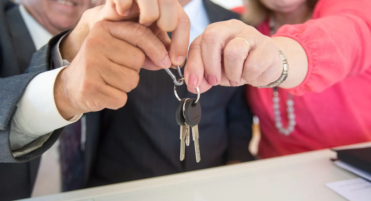 Business colleagues celebrating a successful deal with a handshake and keys exchange.