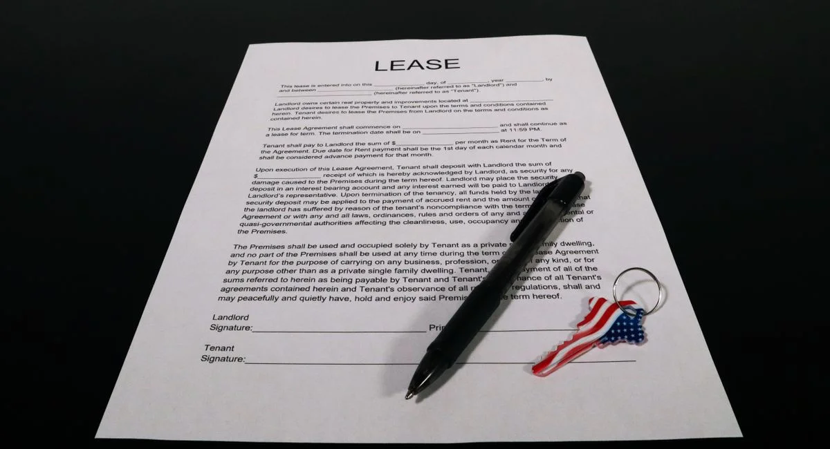 Lease agreement document with pen and American flag keychain on a black table.