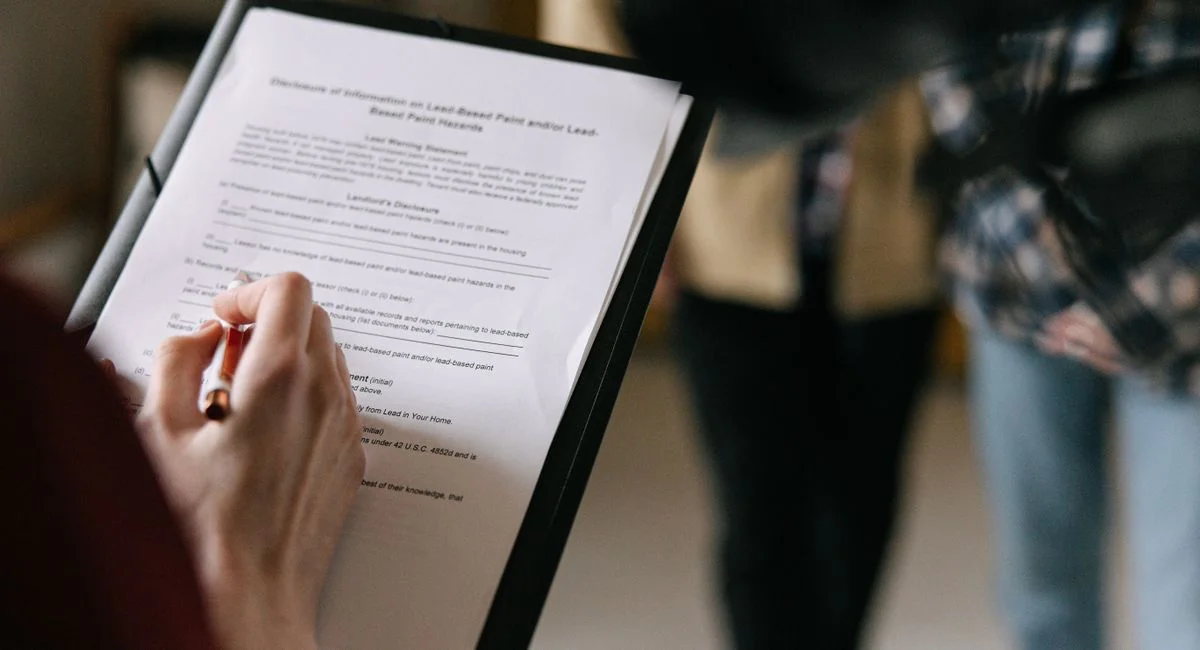 A couple examines real estate documents indoors with focus on writing and discussion.