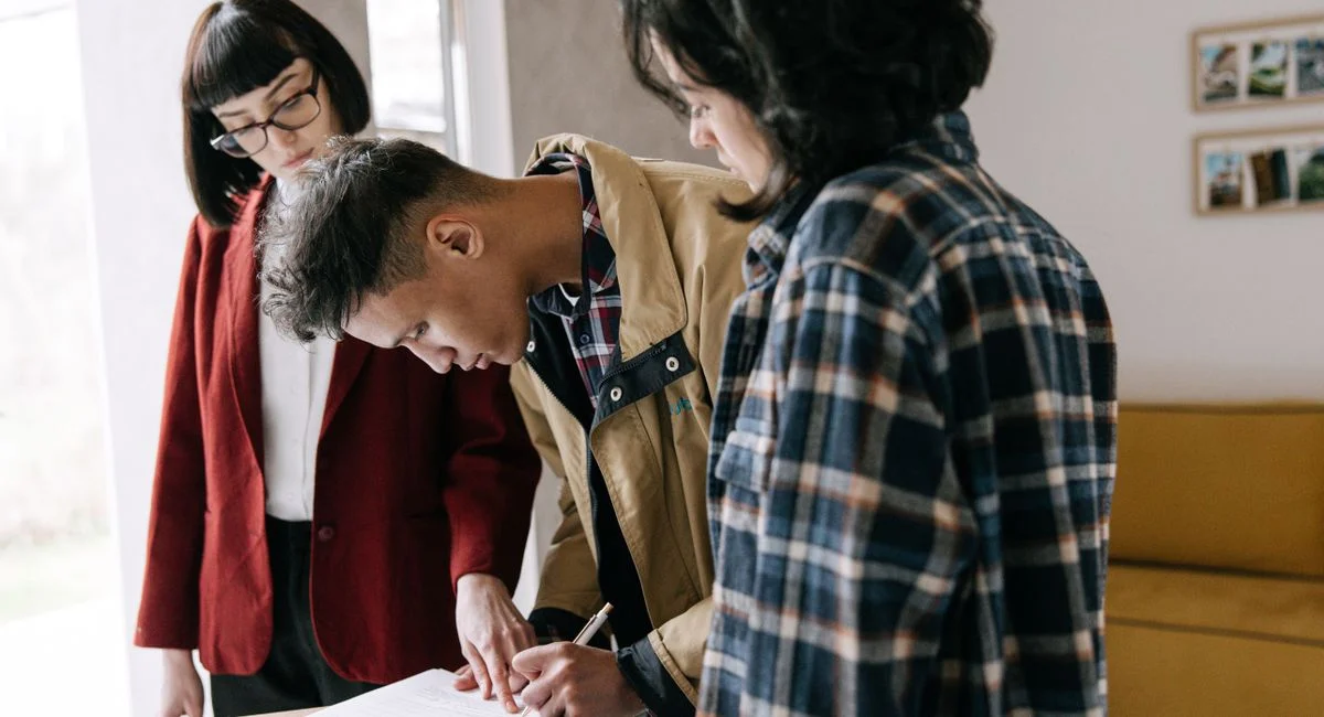 Young couple signing a real estate agreement with an agent indoors.