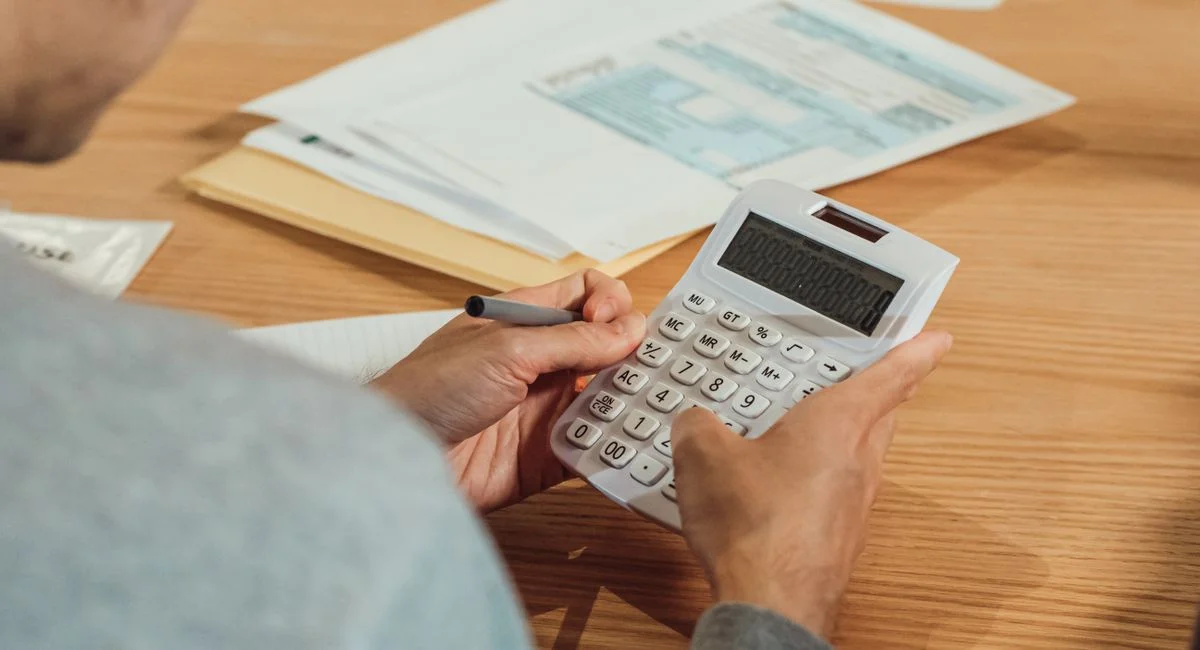 Person using a calculator at a desk with financial documents. Modern business concept.