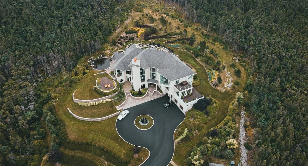 Drone shot of a luxurious house surrounded by dense forested landscape.